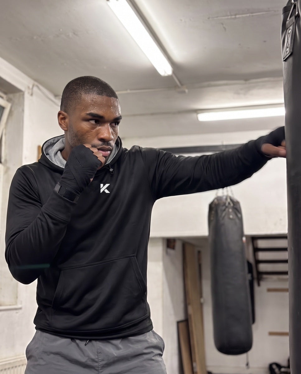 Man in the black Pro Sauna Hoodie and gray shorts throwing a jab in front of a gym mirror